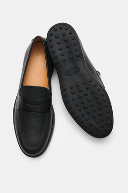 Tod's Penny Loafer schwarz, aus geschmeidigem Leder, schmal zulaufende Silhouette, typischer Penny Strap, Steppnaht auf Vorderkappe, Gummisohle mit Noppen, von oben und unten fotografiert.