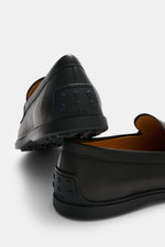 Tod's Penny Loafer schwarz aus geschmeidigem Leder, schmal zulaufende Silhouette, Penny Strap, Steppnaht Vorderkappe, Gummisohle mit Noppen, Rückansicht.