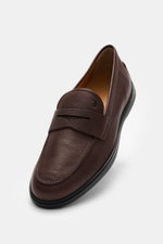 Tod's Penny Loafer braun aus geschmeidigem Leder mit schmal zulaufender Silhouette, typischem Penny Strap, Steppnaht auf der Vorderkappe, markentypischer Gummisohle mit Noppen, seitliche Draufsicht.