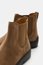 Close-up rear side view of Tod's Chelsea Boot light brown made of soft suede leather, slightly narrow tapered, with side elastic inserts, leather lining, practical pull tab, and typical studded rubber sole.