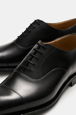Close-up, top-front angled view of Church's Oxford shoes 'Consul' black in polished calf leather with cap toe and closed five-eyelet lacing.

Description: 
<p>Add a luxurious, stylish finish to your formal outfits with these timeless Oxford shoes by CHURC