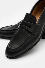 Close-up front-side view of Church's Penny Loafer 'Milton' black in supple leather with classic silhouette and penny strap.

Description:  
<p>The Penny Loafer 'Milton' by CHURCH'S impresses with its supple leather and classic silhouette – perfect for sty