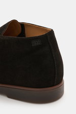 Nahaufnahme von der Ferse des Fabiano Ricci Desert Boot dunkelbraun aus edlem Veloursleder, leicht schmal zulaufende Silhouette, dezente RFR-Prägung an der Seite, Innenfutter aus Leder und flexible Gummisohle, fotografiert aus seitlicher Perspektive.
