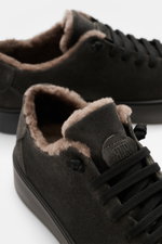 Close-up front-side view of Fabiano Ricci Sneaker 'Tennessee' dark grey showing soft suede leather, elastic seven-eyelet lacing, round toe, lambskin lining, padded insole, embossed tongue logo, and flexible rubber sole, designed for quick slip-on comfort.