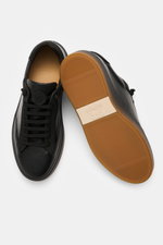 Fabiano Ricci Sneaker 'Double TDM' schwarz aus genarbtem Leder, von oben fotografiert, zeigt runde Vorderkappe, elastische Sieben-Loch-Schnürung und flexible braune Gummisohle.
