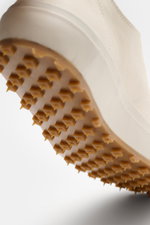 Close-up low-angle view of the Officine Creative Sneaker 'Vulcan' offwhite showing the finely grained leather upper and studded rubber sole. Modern retro look with round toe cap, seven-eyelet lacing, logo-embossed tongue, leather lining, and nubby rubber 