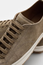 Close-up side and top view of Officine Creative Sneaker 'Vulcan' taupe in noble suede with round toe, seven-eyelet lacing, logo-embossed tongue, leather lining, and textured rubber sole, showcasing a modern retro look for office and leisure outfits.