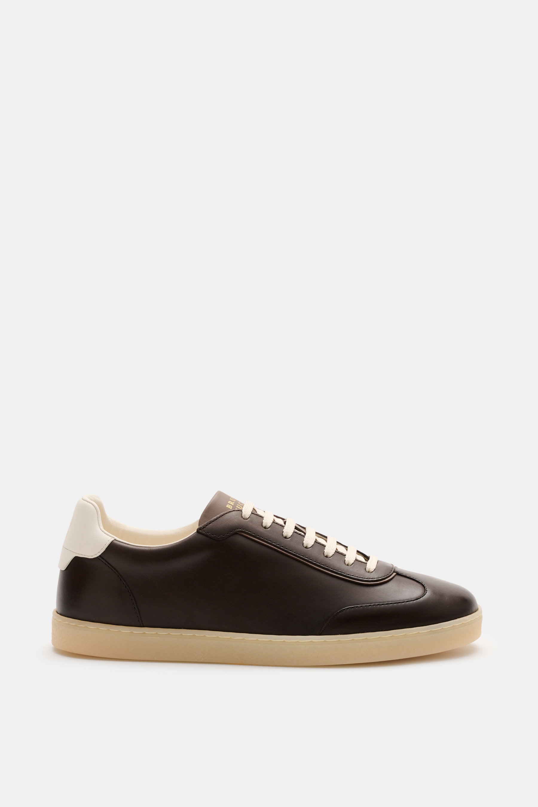 Brunello Cucinelli Sneaker dunkelbraun aus geschmeidigem Leder mit schlanker Silhouette, Flügelkappe, Sieben-Loch-Schnürung, goldfarbener Prägung, gepolstertem Schaftrand, Glattlederfutter und Gummisohle, seitliche Nahaufnahme.