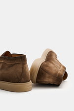 Santoni Desert Boot 'Detroit' braun aus geschmeidigem Veloursleder, flexible Gummisohle, schmale Silhouette, Ziernaht, von schräg hinten fotografiert.
