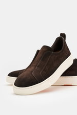 Santoni Slip-on-Sneaker 'Victory' dunkelbraun aus geschmeidigem Veloursleder, leicht schmal zulaufend, mit Gummizug, Anziehschlaufe, Logoprägung, Lederfutter, Gummisohle, seitliche Nahaufnahme.