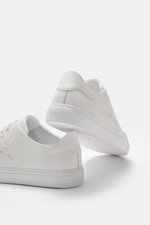 Axel Arigato Sneaker 'Clean 90' weiß shown from rear and side view, featuring smooth leather, round toe, velour overlay, seven-hole lacing, gold label, hummingbird embroidery, padded collar, contrasting heel overlay, leather lining, and flexible rubber so
