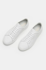 Axel Arigato Sneaker 'Clean 90' weiß shown from a top-front angle, featuring clean Scandinavian design, smooth leather, round toe, seven-eyelet lacing, gold label embossing, padded collar, leather lining, and flexible rubber sole. <p>Mit seinem cleanem sk