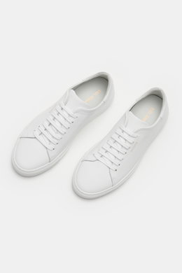 Axel Arigato Sneaker 'Clean 90' weiß shown from a top-front angle, featuring clean Scandinavian design, smooth leather, round toe, seven-eyelet lacing, gold label embossing, padded collar, leather lining, and flexible rubber sole. <p>Mit seinem cleanem sk