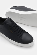 Close-up side and sole view of Axel Arigato Sneaker 'Clean 90' schwarz in black smooth leather with tonal suede detail, seven-hole lacing, rounded toe, padded collar, gold label embossing, leather lining, and flexible white rubber sole.

<p>Bei dem Sneake