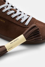 Close-up, top-front angled view of Axel Arigato Sneaker 'Zane' braun in soft brown velour with white laces, extra brown laces beside. <div class="qMYqUG_convSearchResultHighlightRoot">
<div class="" data-turn-id-container="request-WEB:32f1fab7-4f78-4689-