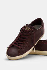Golden Goose Sneaker 'Super-Star Classic' bordeaux, schräg von oben, Nappaleder, Vintage-Finish, Stern, Used-Optik, flexible Gummisohle, perforierte Seiten.