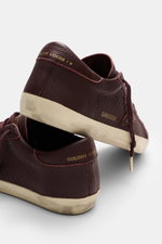 Golden Goose Sneaker 'Super-Star Classic' bordeaux aus feinem Nappaleder mit Vintage-Finish, Used-Optik, Stern, Logo und Gummisohle, Rückansicht.