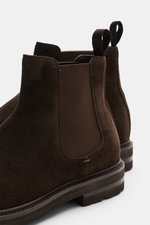 Close-up rear side view of Henderson Chelsea boots dark brown in premium suede with elasticated inserts and pull-on tabs, Blake design.

Description: A symbol of confident British style, perfected by Italian design: These classic Chelsea boots in fine sue