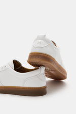 Rear and side view of Henderson Sneaker 'Vitello' white in noble smooth leather with rounded toe cap, six-eyelet lacing, logo embossing on tongue, leather lining, and light rubber outsole, photographed from a low angle.