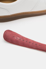 Close-up side view of the Henderson Sneaker 'Vitello' white showing noble smooth leather, rounded toe cap, six-eyelet lacing, logo embossing on the tongue, leather lining, and light rubber outsole.