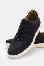 Tod's Slip-on Sneaker navy aus softem Veloursleder mit elastischer Schnürung, gepolstertem Schaftrand, Emblem und genoppter weißer Sohle, seitlich fotografiert.