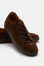 Close-up view of Tod's Slip-on Sneaker dark brown in soft suede leather, showing elastic closed lacing, padded collar, and studded rubber sole.

<p>The slip-on sneaker is indispensable this season. TOD'S sets the example with this model, combining stylish