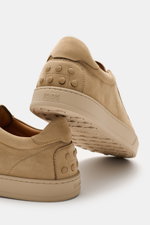 Tod's Slip-on Sneaker beige aus softem Veloursleder, genoppte Gummisohle, elastische Schnürung, Vorderansicht schräg von unten fotografiert.