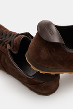 Jacquemus Sneaker 'Les Tennis' dark brown shown from a close-up top and side angle, featuring supple suede leather, seven-eyelet lacing, tongue with logo embossing, overlays made of suede leather, leather lining, and an ultraflexible rubber sole.