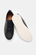 Top and sole view of Zegna Slip-on Sneaker 'Triple Stitch' navy, made of grained leather, with round toe, crisscrossed elastic bands, padded collar, pull tab, embossed tongue, leather lining, and flexible rubber sole.