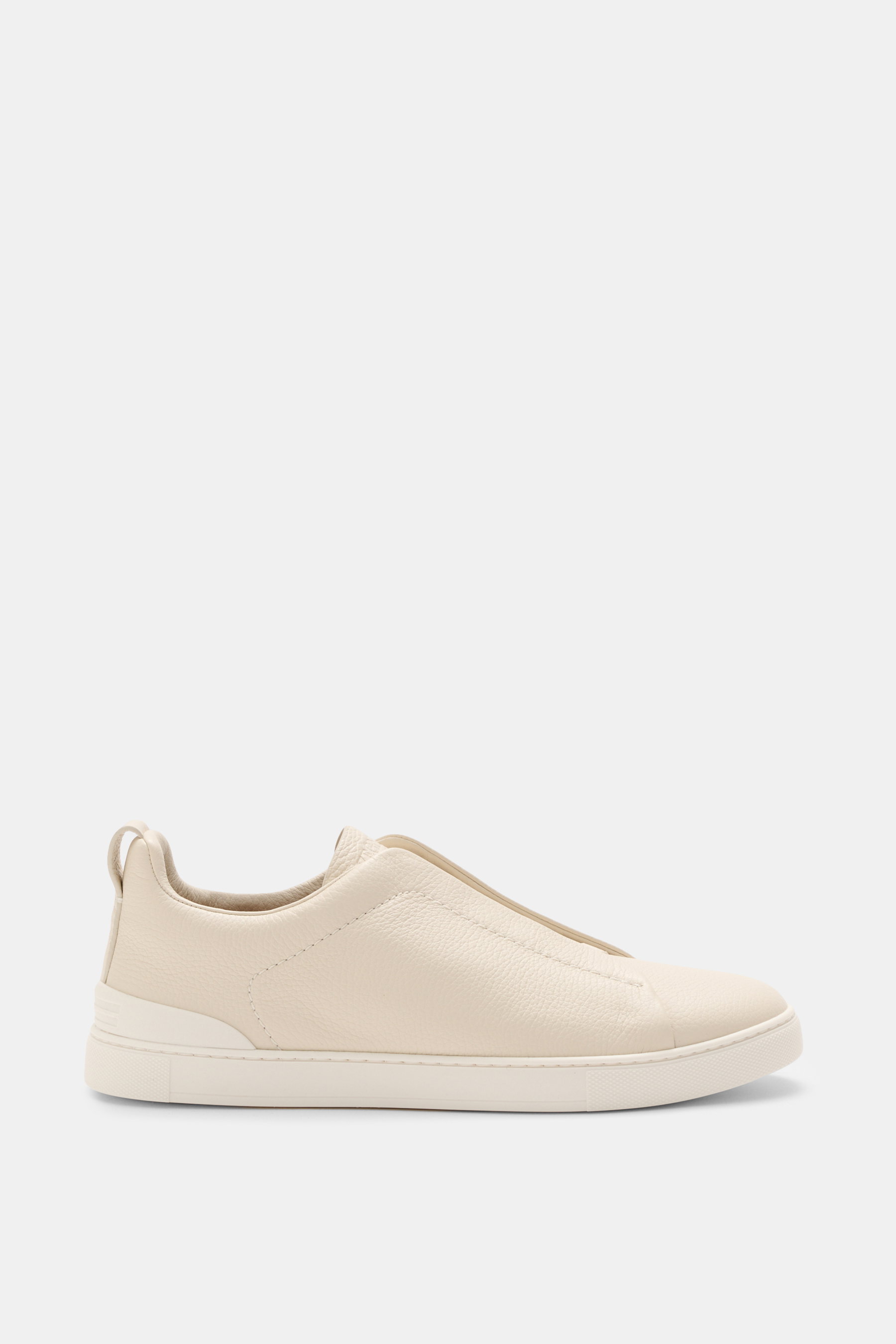 Side view of the Zegna Slip-on Sneaker 'Triple Stitch' sand, made of grained leather with round toe cap, crossed elastic bands, high padded collar, pull tab, ZEGNA embossed tongue, leather lining, and flexible rubber sole.