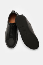 Top-down view of Zegna Slip-on Sneaker 'Triple Stitch' black made of grained leather with round toe cap, crossed elastic bands, high padded collar, pull tab, ZEGNA embossed tongue, leather lining, and flexible rubber sole.