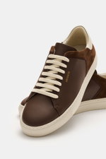 Front angle view of Axel Arigato Sneaker 'Clean 90 Split' dark brown, showcasing smooth and suede leather, rounded toe, seven-eyelet lacing, gold label embossing, padded collar, leather lining, and flexible rubber sole.