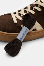 Nahaufnahme des Hogan Sneaker 'Cool Allacciato' dunkelbraun/beige aus Veloursleder mit Sieben-Loch-Schnürung, H-Logo und Memory-Foam-Fußbett, seitliche Perspektive.