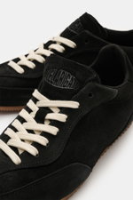 Close-up front-side view of Axel Arigato Sneaker 'Daze Runner' schwarz in black suede with white laces, showcasing tonal overlays and round toe cap. Minimalismus in Bewegung: Der 'Daze Runner' von AXEL ARIGATO interpretiert den Retro-Sneaker auf moderne, 