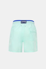 Vilebrequin Swim shorts 'Moka' mint green/dark blue shown from the back, featuring elastic waistband, side and back pockets, drainage eyelets, turtle stitching, VILEBREQUIN label, mesh lining, and high-quality microfibre for comfort.