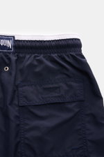 Close-up rear view of Vilebrequin Swim shorts 'Moka' navy, showing elastic waistband, back pocket with hook-and-loop fastener, drainage eyelets, and high-quality microfibre fabric. The swim shorts feature a regular fit, turtle stitching on the thigh, side