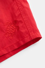 Close-up from above of Vilebrequin Swim shorts 'Moorea Magic' red showing tonal turtle stitching on high-quality microfibre fabric that changes color in water.