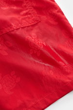 Close-up view of Vilebrequin Swim shorts 'Moorea Magic' red made of high-quality microfibre with tonal turtle stitching; the fabric changes color on contact with water. Features include a regular fit, elasticated waistband with drawstring, side seam pocke