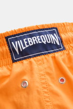 Nahaufnahme aus seitlicher Perspektive der elastischen Bundpartie mit Tunnelzug und VILEBREQUIN-Label der orangefarbenen Vilebrequin Badeshorts 'Moorea Magic' aus wasserreaktiver Microfaser.