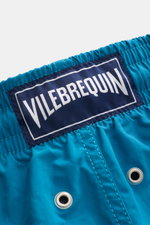 Nahaufnahme der elastischen Bundzone der Vilebrequin Badeshorts 'Moorea Magic' petrol mit blauem VILEBREQUIN-Weblabel, wasserreaktiv, aus hochwertiger Microfaser.
