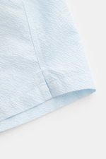 Close-up side view of the hem and side vent of 04651/ A trip in a bag Swim shorts 'Mono Seersucker' pastel blue in textured seersucker fabric.

<p>Perfect for your next summer holiday: With their design in seersucker look, these swim shorts by 04651/ A TR