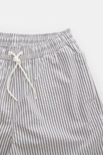 Close-up top-front view of 04651/ A trip in a bag Swim shorts navy/white striped with elasticated waistband, drawstring, and seersucker fabric.

<p>Perfect for your next summer holiday: With their modern striped pattern, these swim shorts by 04651/ A TRIP