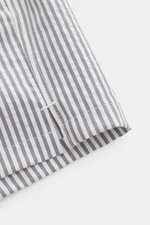 Close-up side view of 04651/ A trip in a bag Swim shorts navy/white striped hem with side vents, showing striped seersucker fabric.

<p>Perfect for your next summer holiday: With their modern striped pattern, these swim shorts by 04651/ A TRIP IN A BAG ar