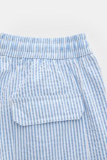 Close-up rear view of 04651/ A trip in a bag Swim shorts blue/white striped showing elastic waistband, back pocket with flap and striped seersucker fabric.

<p>Perfect for your next summer holiday: With their modern striped pattern, these swim shorts by 0