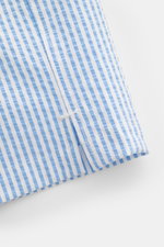 Close-up view of the hem with side vents of the 04651/ A trip in a bag Swim shorts blue/white striped, showing the seersucker fabric texture and vertical stripes. 

<p>Perfect for your next summer holiday: With their modern striped pattern, these swim sho