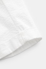 Close-up bottom side view of 04651/ A trip in a bag Badeshorts 'Plain Swim' off-white made of soft, quick-drying microfiber with contrast stitching. The shorts feature a regular fit, tunnel waistband, side seam pockets, back pocket with Velcro, small wove