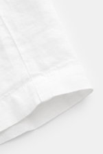 Close-up front-side view of the hem and texture of 04651/ A trip in a bag Linen bermudas 'Linen Bermuda' white, showcasing pure linen fabric and soft feel. These airy Bermudas by 04651/ A TRIP IN A BAG are a must-have for your next beach holiday. The flex