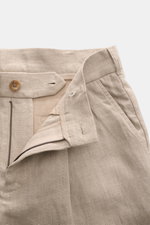 Nahaufnahme der geöffneten Taille der Ché Leinenshorts 'Nevis' beige, aus reinem Leinen mit Reißverschluss, Bundknopf und weicher, strukturierter Oberfläche.