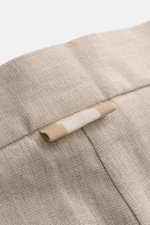 Nahaufnahme der Bundpartie der Ché Leinenshorts 'Nevis' beige, mit sichtbarer materialtypischer Leinenstruktur und kleinem Grosgrain-Detail, fotografiert aus seitlicher Perspektive.