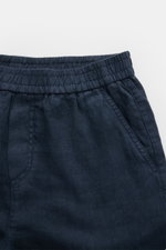 Nahaufnahme der 04651/ A trip in a bag Leinenshorts navy aus reinem Leinen mit elastischem Bund, französischen Taschen und weichem Griff, frontal fotografiert.